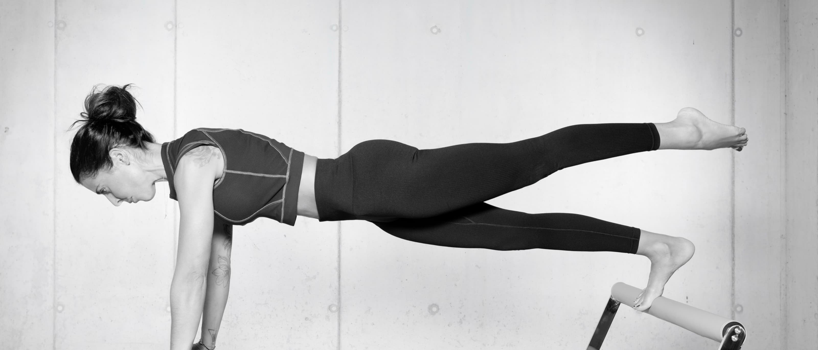 Planche sur le Reformer, une jambe tendue à l'horizontale — lignes longues