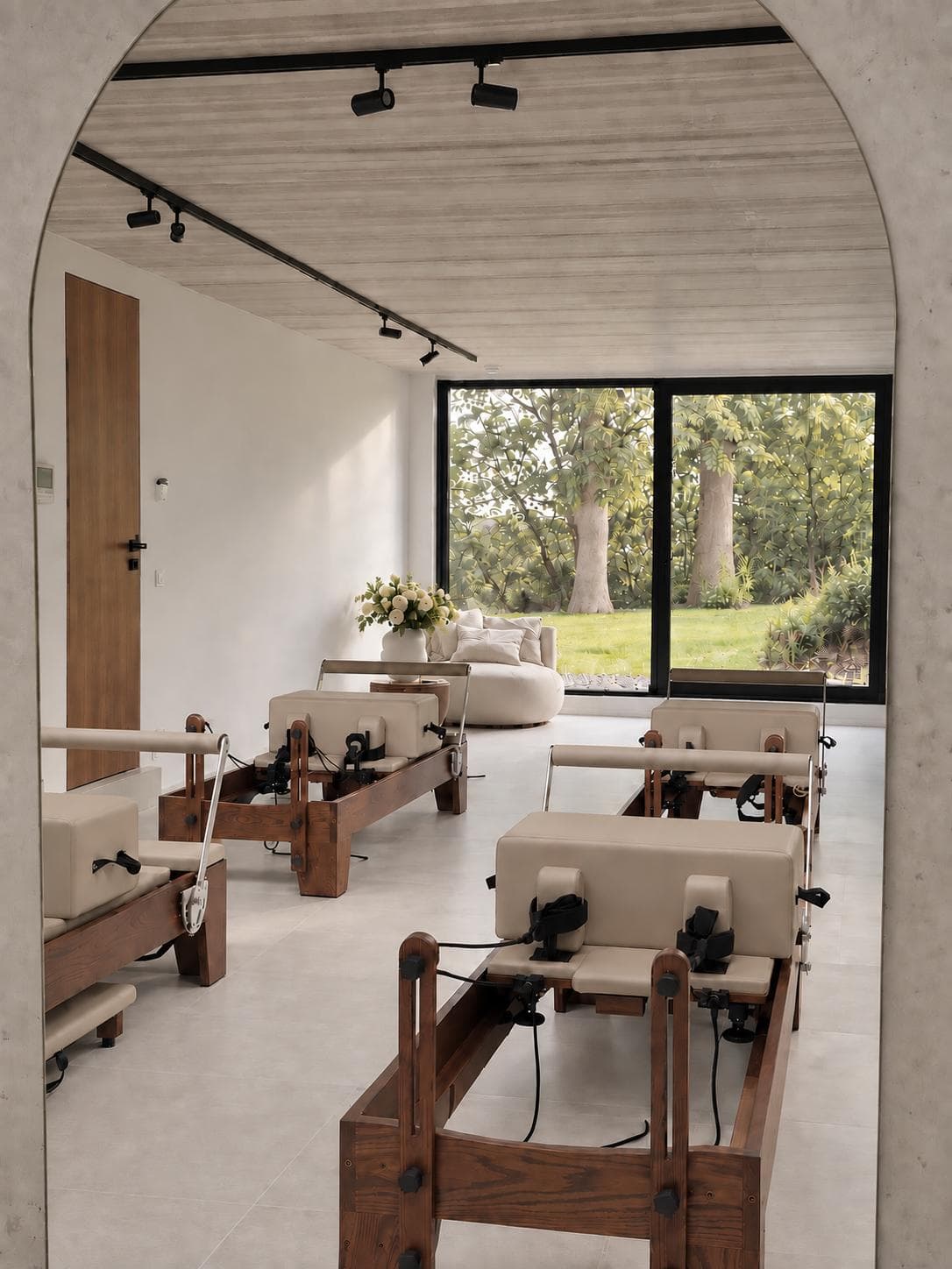 L'arche d'entrée du studio, les Reformer et la baie vitrée sur le jardin