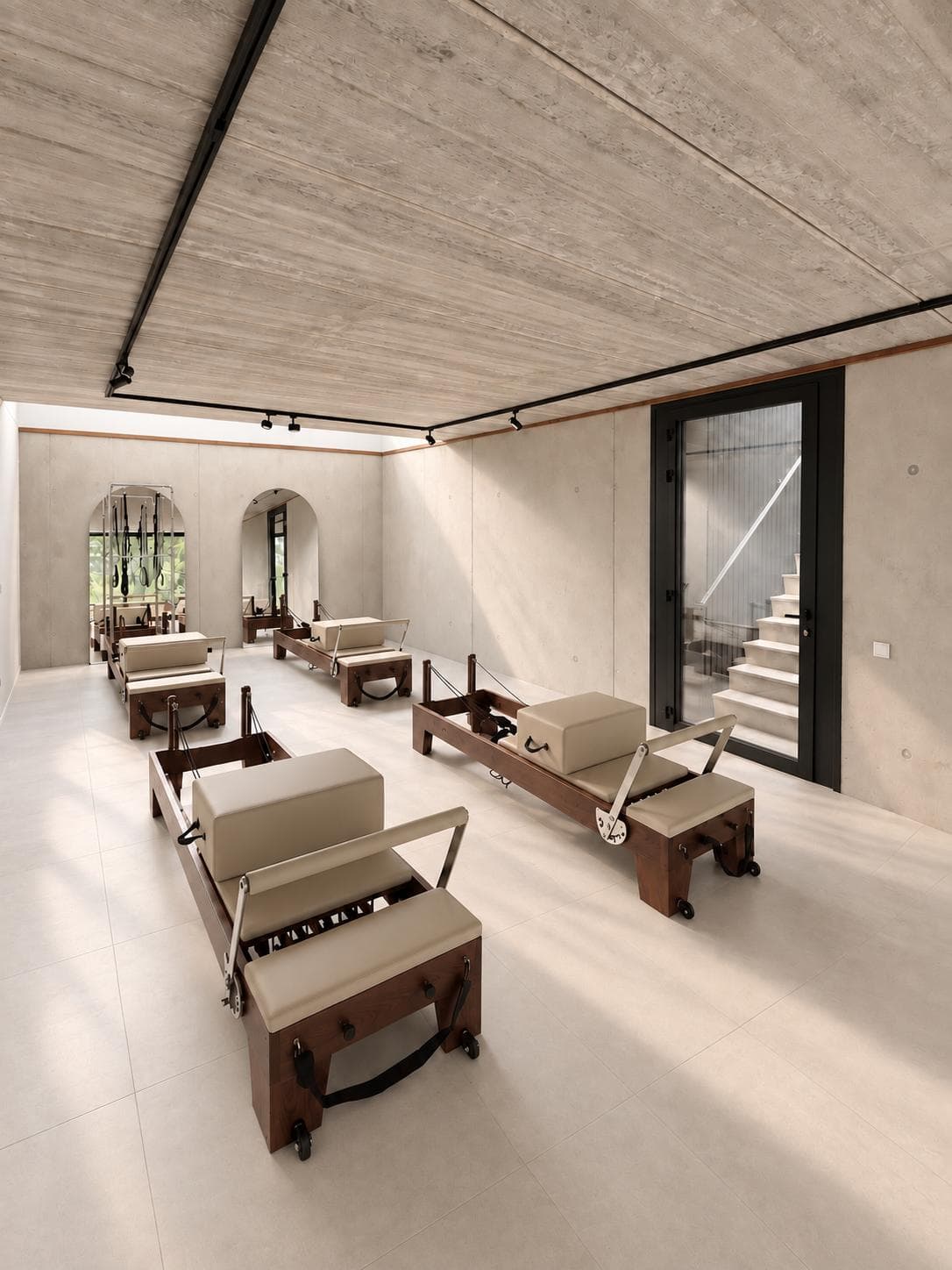 La salle en enfilade : plafond en béton, Reformer en bois, escalier vitré